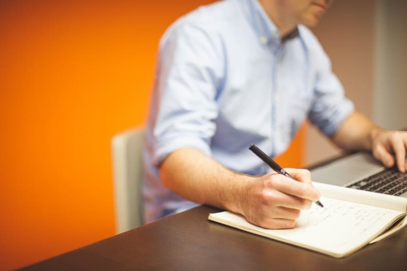 A man is sitting down and writing