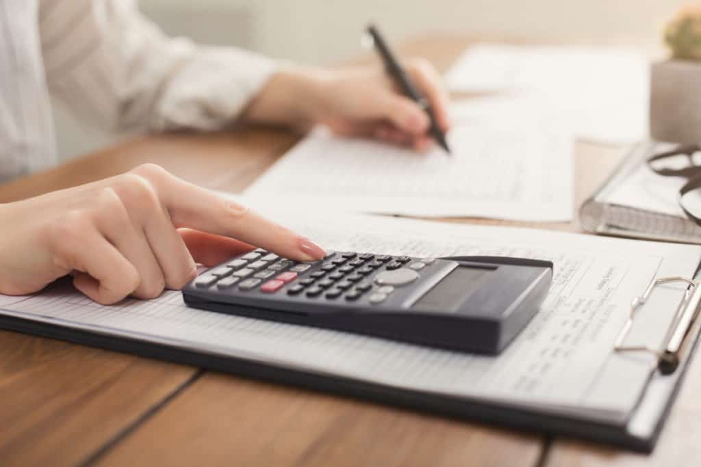 close up of a person using a calculator and writing down numbers