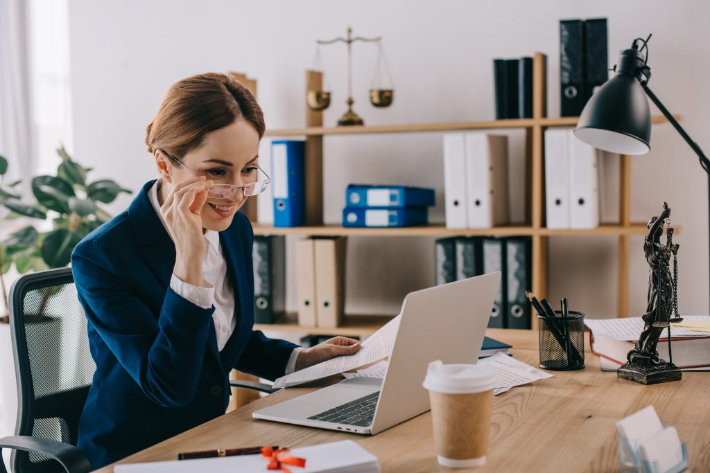 a smiling female lawyer looking at laptop screen at workplace in office