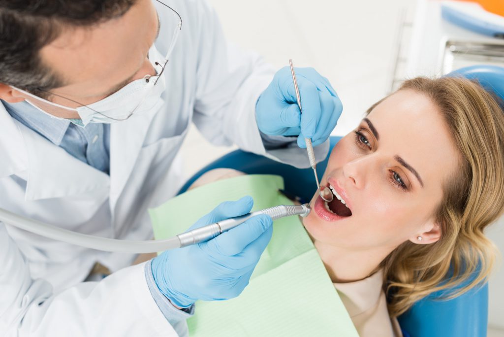 Female patient at dental procedure using dental drill in modern dental clinic