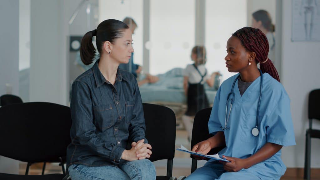 Woman talking to medical assistant in waiting area